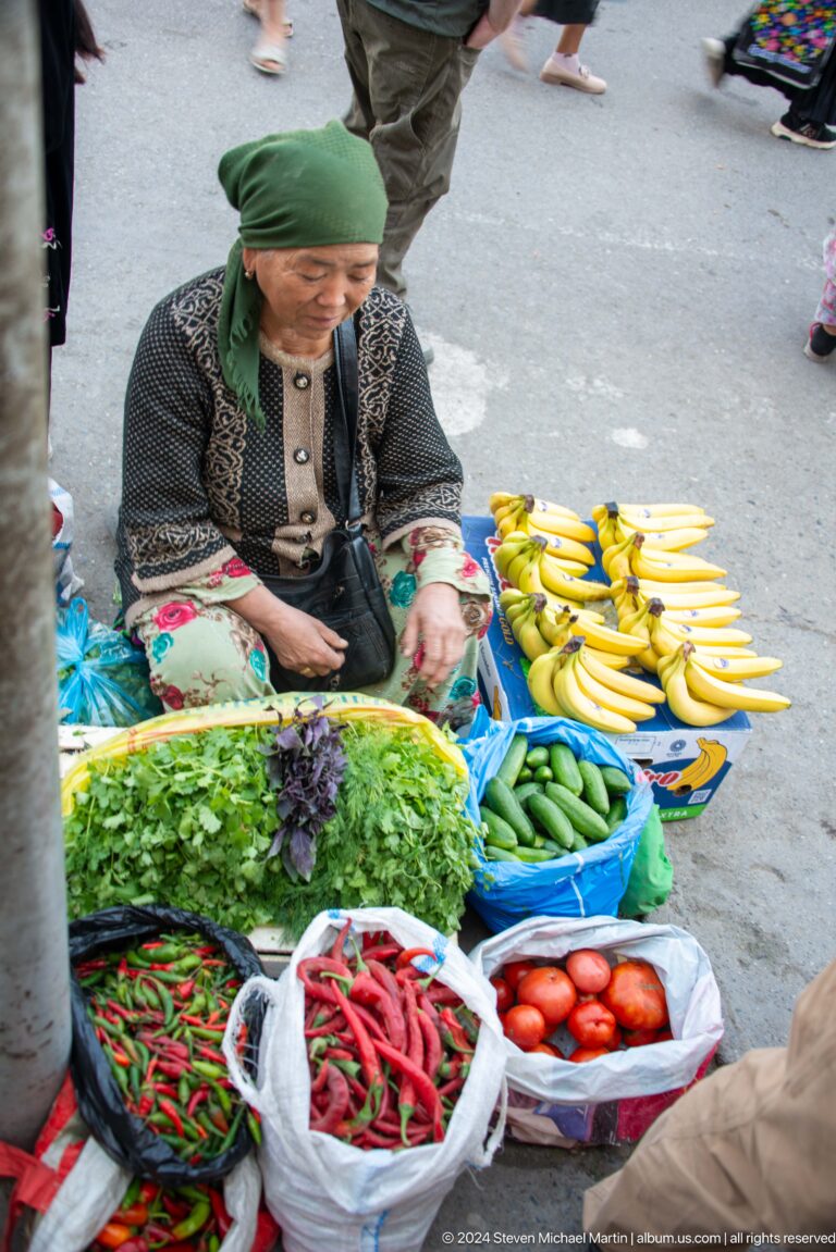 Market display of bananas, cucumbers, greens, and bagged goods.