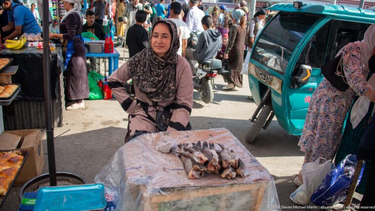 Woman selling fish from a market table.
