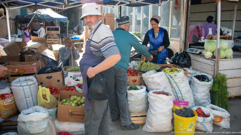 Dry-goods vendor surrounded by sacks and buckets.