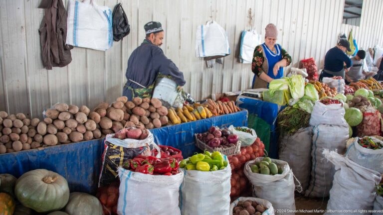 Indoor produce stall with potatoes, citrus, and root vegetables.