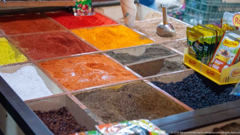 Open bins of red, orange, black, and tan spices.