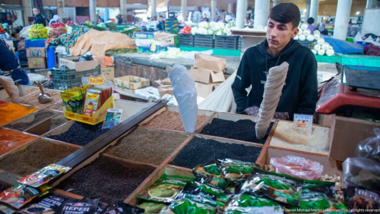 Young male vendor bagging goods behind a dry-food counter.