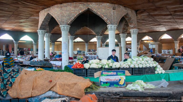 Covered market hall with pointed arches and produce counters.