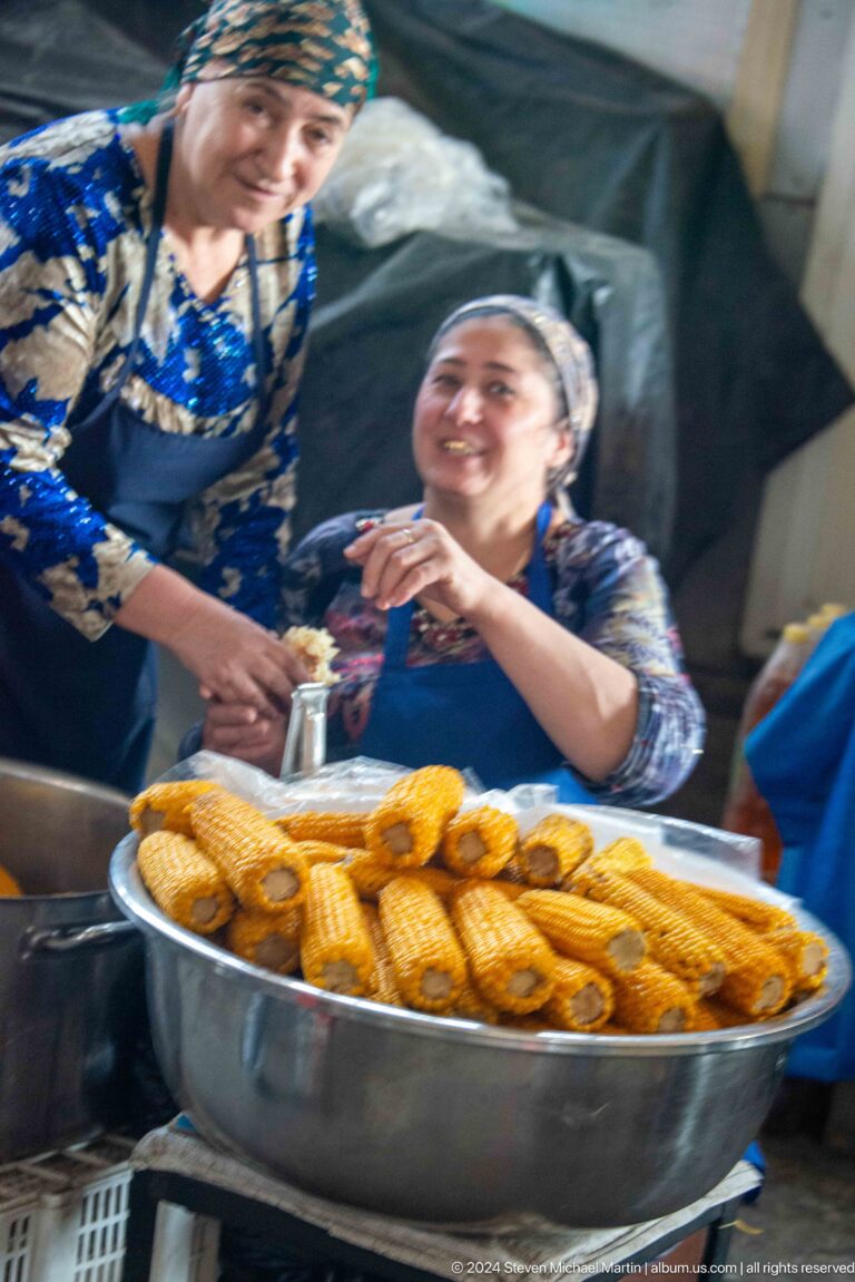 Smiling woman vendor serving rings of bread.