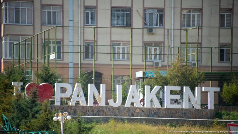 Large PANJAKENT city-name sign in landscaped grounds.