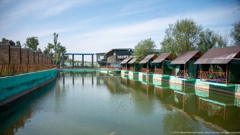 Waterside recreation complex with rows of wooden cabins.