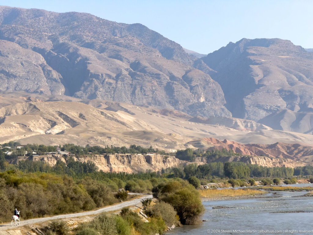 Broad river valley beneath steep eroded mountains.