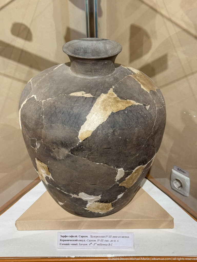 Large dark globular storage jar with narrow neck and extensive pale restoration fills.