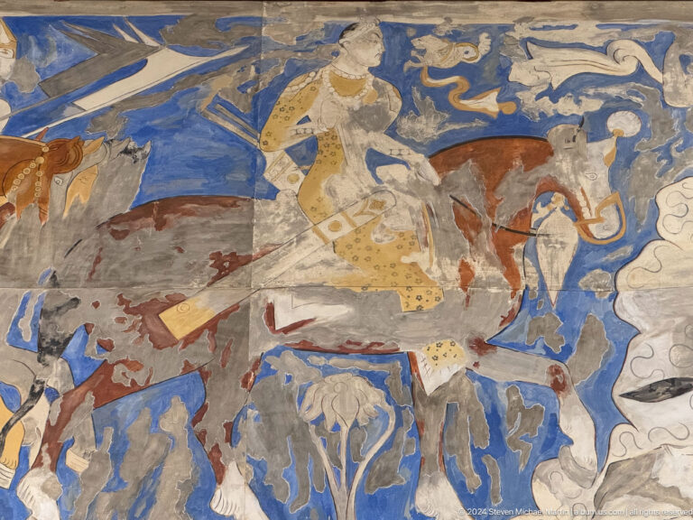 Fragmentary blue mural with a mounted figure, several horses, and small animals.