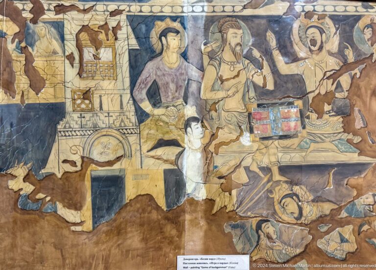 Fragmentary mural of richly dressed figures gathered around a low table.