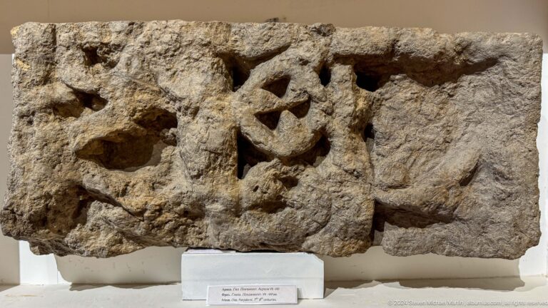 Weathered stone fragment carved with a central rosette and triangular openings.
