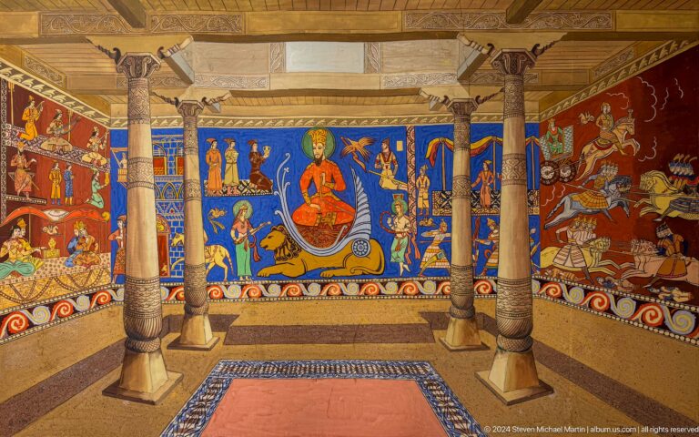 Reconstructed columned room with vivid blue, red, and ocher wall paintings.