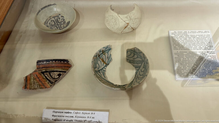 Curved painted ceramic fragments with black, white, green, and red decoration.