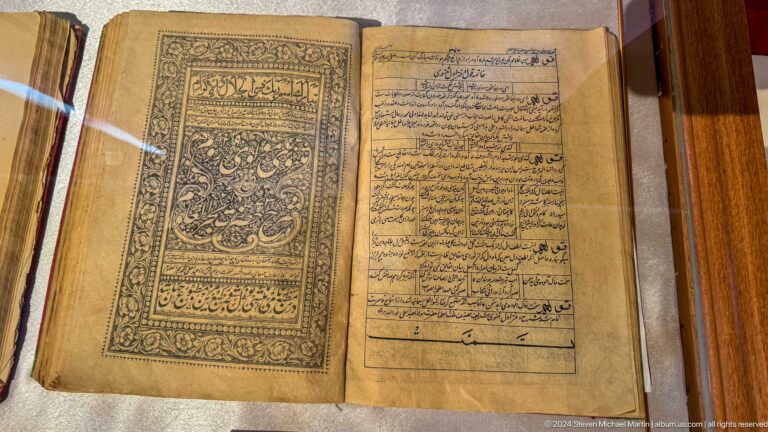 Open manuscript with dense script and an ornate decorative border on one page.