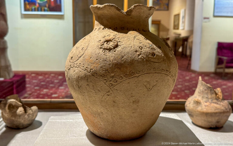 Large beige ceramic jug with a handle, narrow neck, and decorated shoulder.