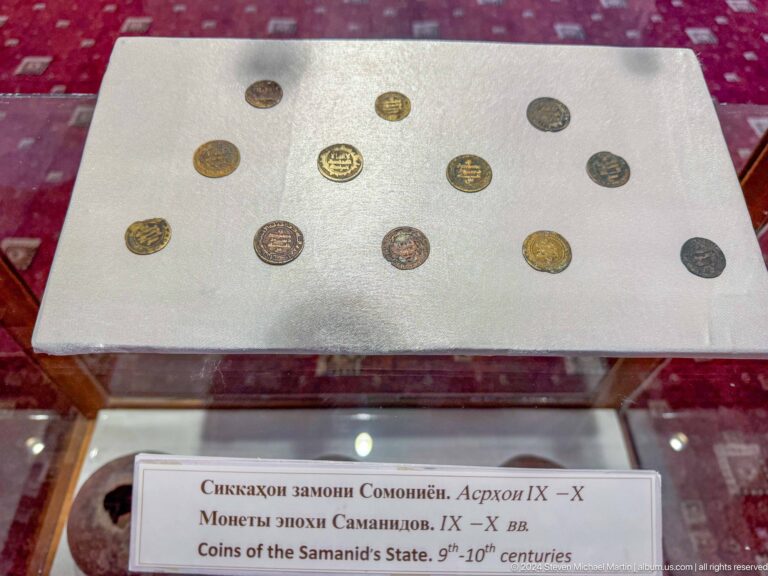 Small medieval coins of different sizes arranged in three rows on a white mount.