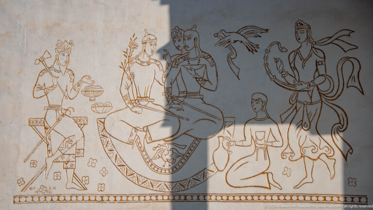 Line mural of a large seated figure with attendants, vessels, birds, and smaller figures.