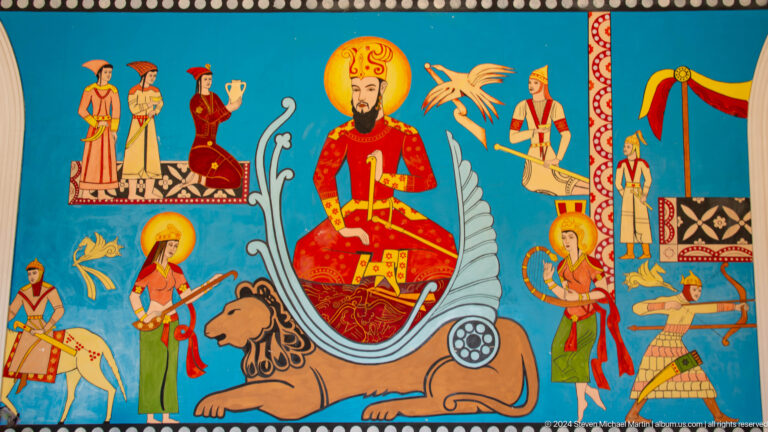 Colorful panel with a crowned red-robed figure, lion, birds, attendants, and smaller narrative scenes.