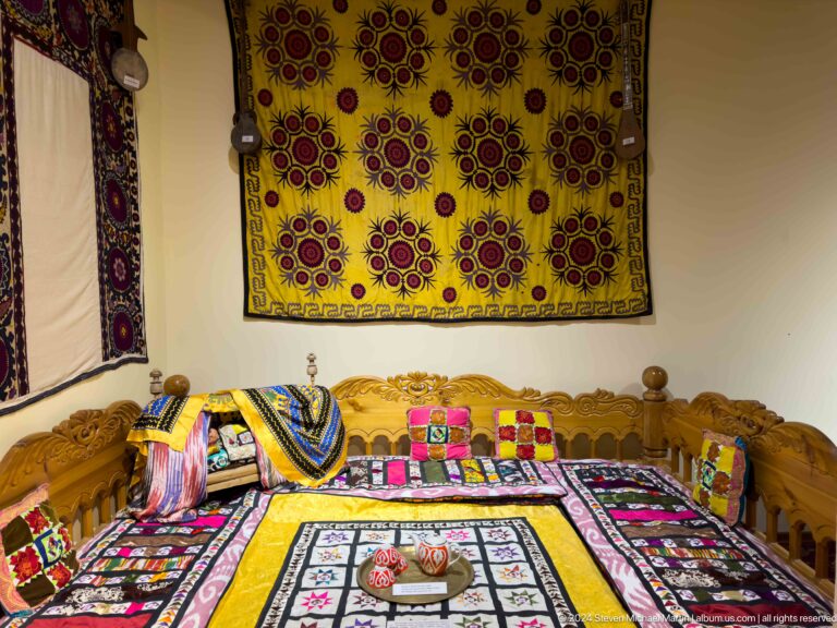 Traditional room with a patterned wall hanging, colorful cushions, low seating, and a central table.