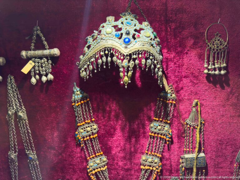 Turquoise ceremonial headdress, necklaces, earrings, and pendants arranged on magenta velvet.