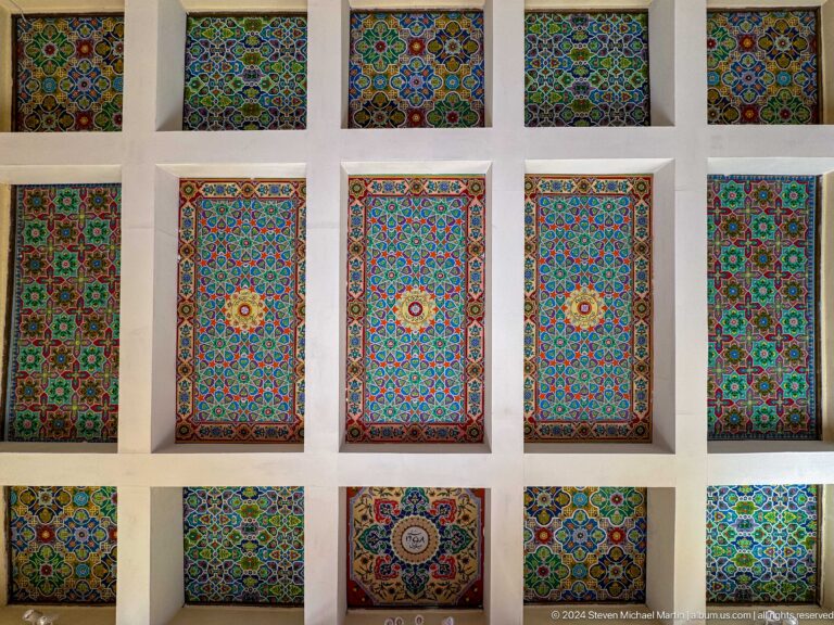 Grid of framed blue, green, and red geometric panels with stars, rosettes, and interlace.