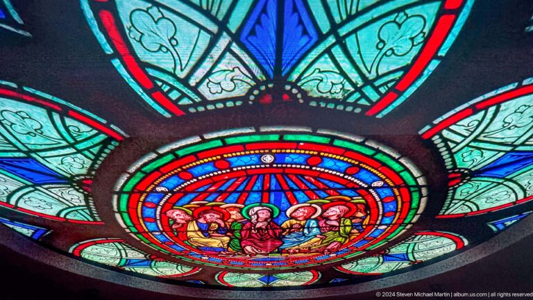 Circular stained-glass-style digital display showing central human figures within vivid red, blue, and turquoise concentric rings at the Abrahamic Family House.