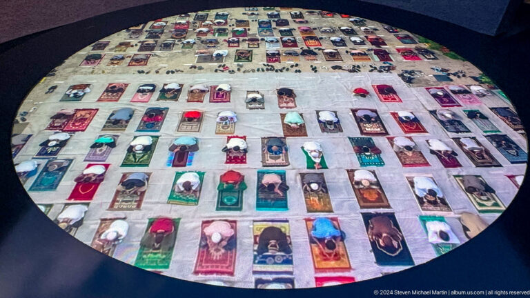 Overhead view of a circular installation filled with many brightly colored rectangular book-like objects arranged in a dense mosaic at the Abrahamic Family House.
