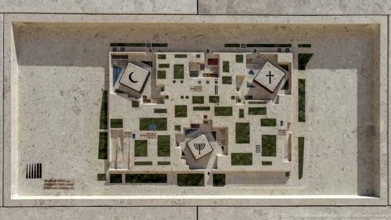Overhead view of the Abrahamic Family House site model with three main buildings arranged around a shared garden, connected by paths and landscaped courtyards.