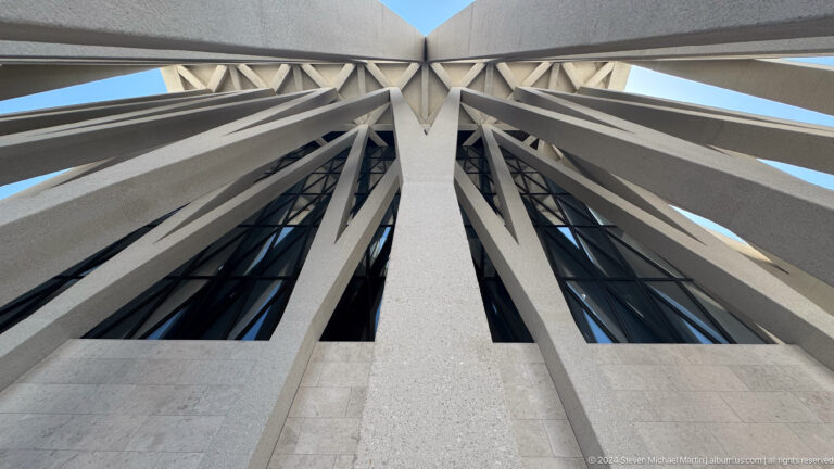 Upward view of the Abrahamic Family House roof showing white structural beams converging around a dark glazed skylight.
