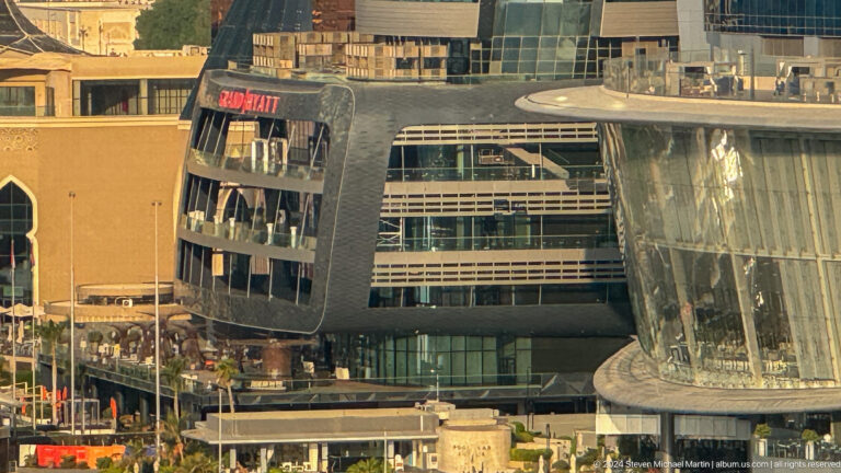 Telephoto view of a high-rise building under construction on the Abu Dhabi waterfront, with exposed floors, scaffolding, and cranes along the facade.