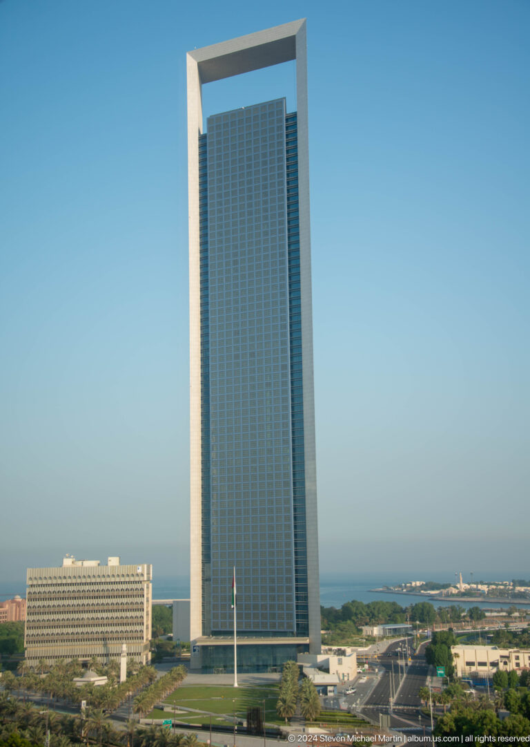 Tight daytime view of Etihad Towers in Abu Dhabi, showing closely spaced blue-green glass high-rise facades with curved reflective curtain walls and vertical mullions filling the frame.
