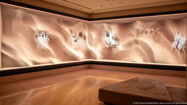 Curved panoramic digital exhibition at The Founder's Memorial with moving imagery projected along the wall and a low bench following the arc of the gallery.