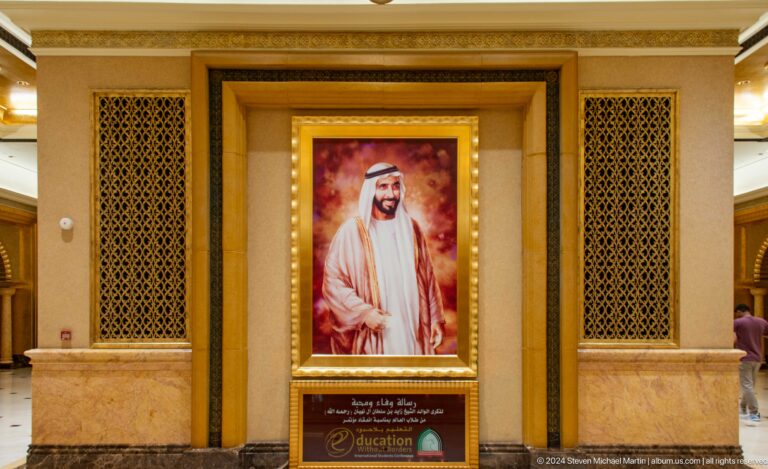 Framed official portrait of a UAE leader in white dress set in an ornate gold wall niche with decorative lattice panels at Emirates Palace.