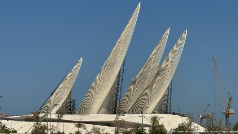 Daytime close view of three tall, tapering perforated pavilion elements at Wahat Al Karama in Abu Dhabi, rising at slightly different angles.