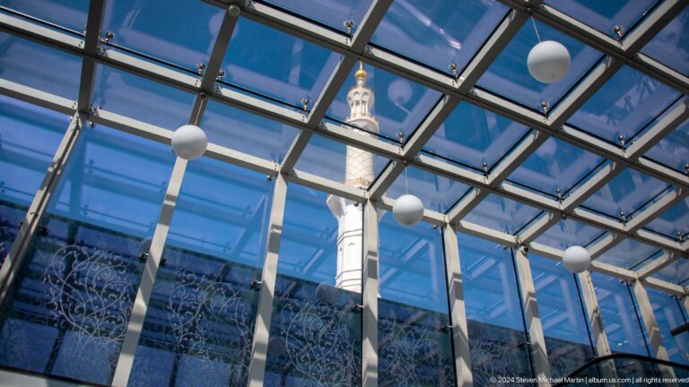 White minaret seen through a blue glass roof grid.