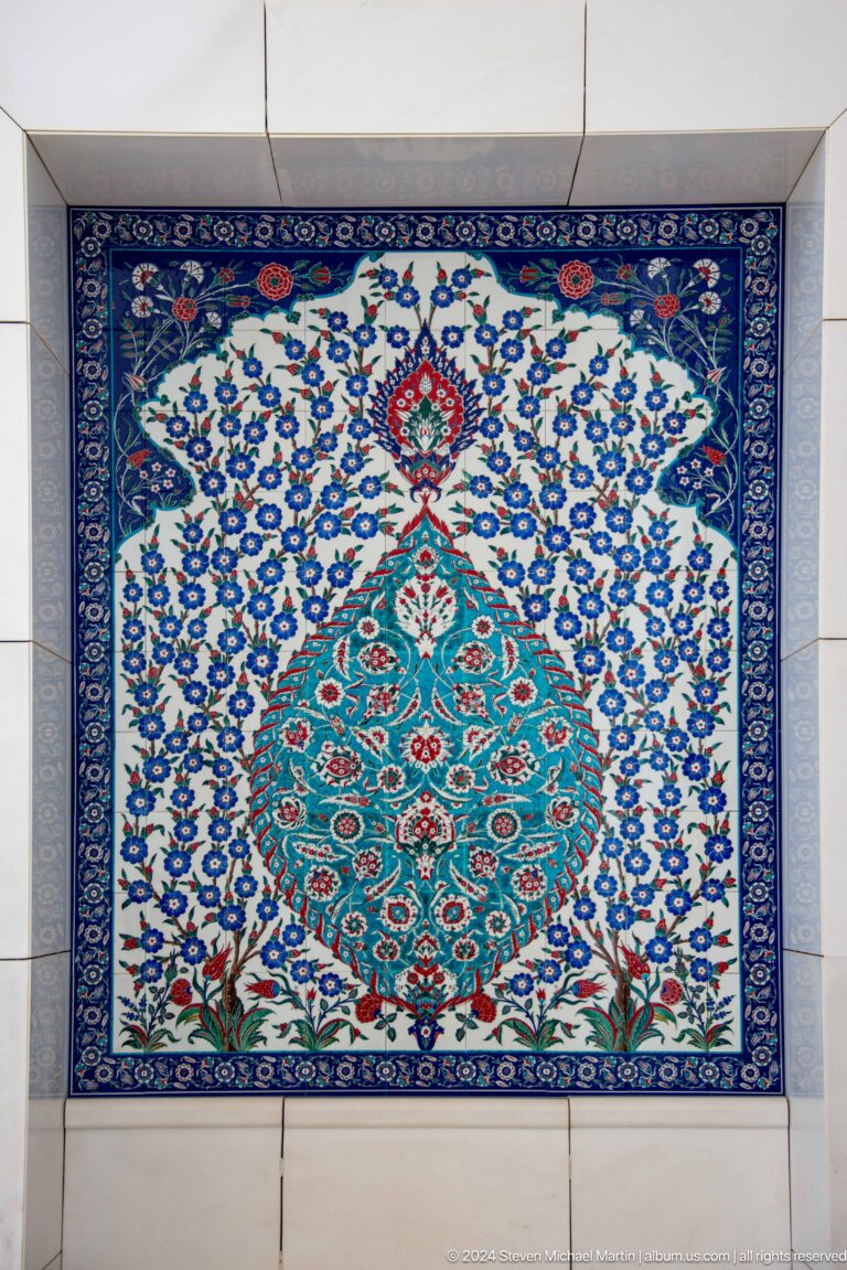 Blue, turquoise, red, and white tile panel with dense floral and geometric ornament.