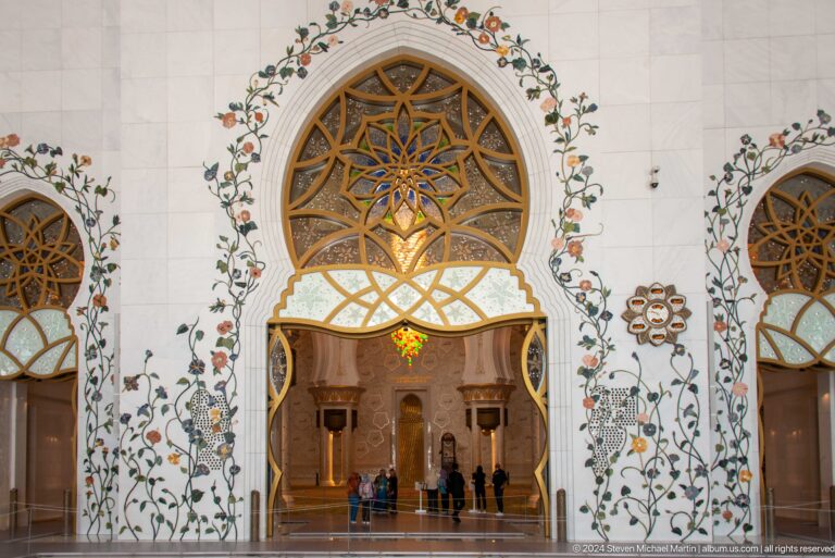 Arched doorway framed by floral inlay and a gold geometric lattice.