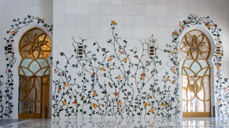 Floral vine inlay on white marble beside a gold geometric lattice.