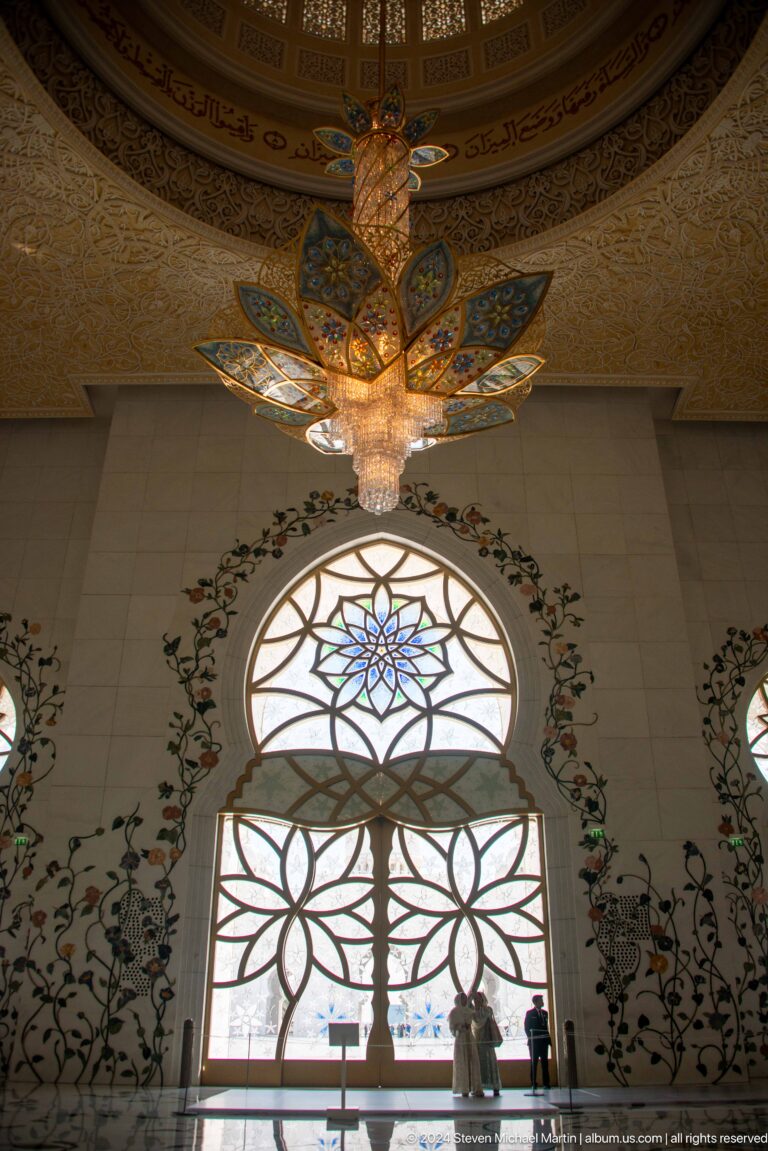 Petal-shaped crystal light above a circular blue-and-green floral window framed by painted vines.