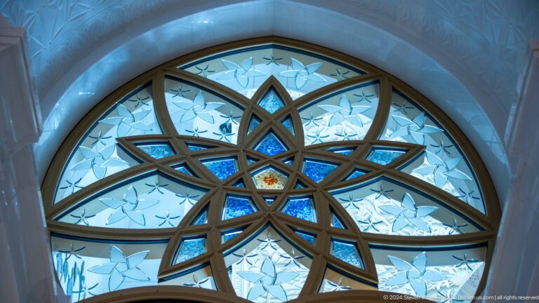Close-up of a blue-glass interlaced star window with pale etched floral panes.