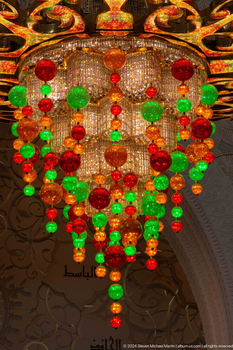 Glowing red, green, and amber glass spheres hang among clear crystal strands.