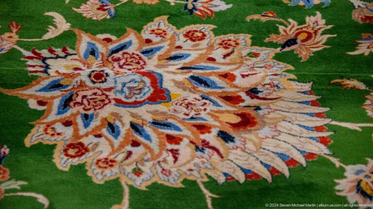 Cream floral medallion with red, blue, and orange accents on a bright green carpet.