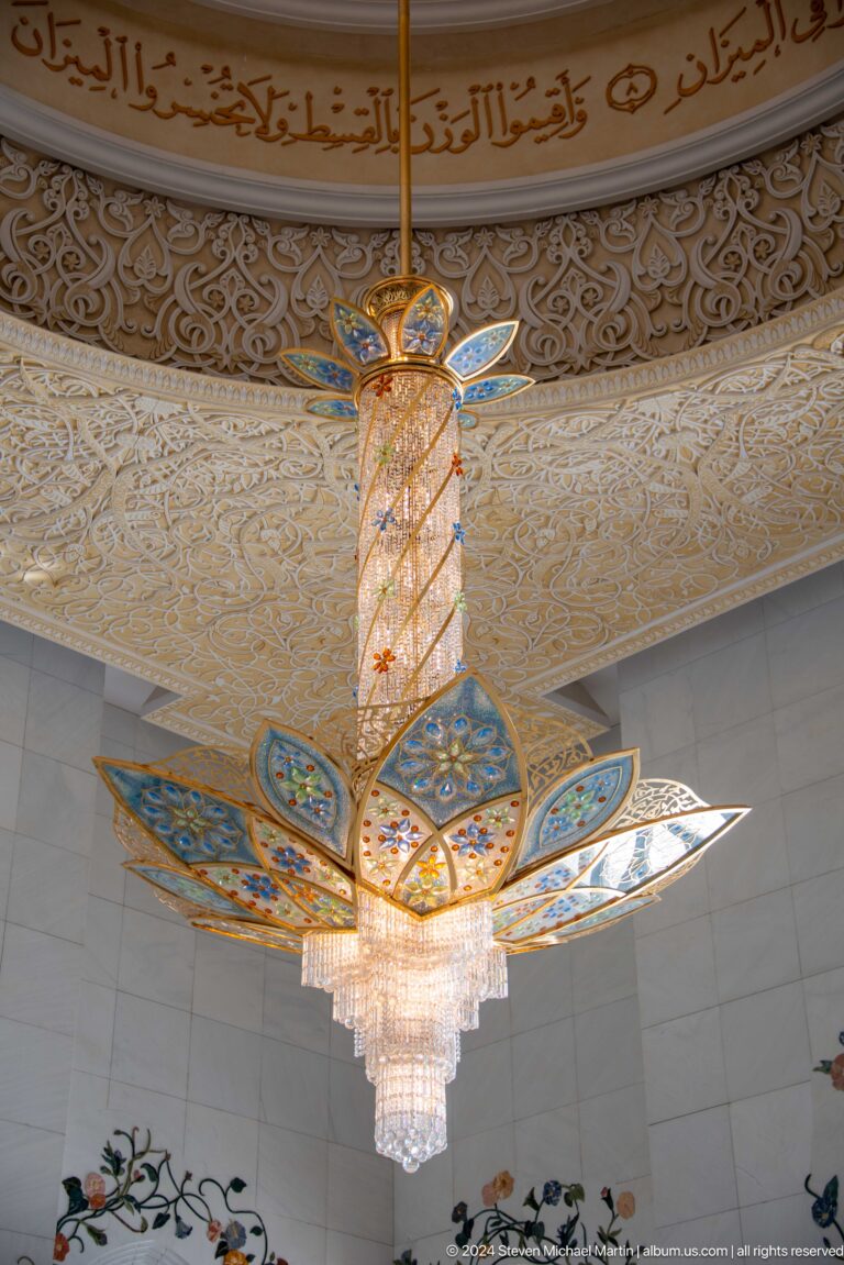 Lotus-shaped crystal light with blue-and-gold petals beneath an ornate cream ceiling.