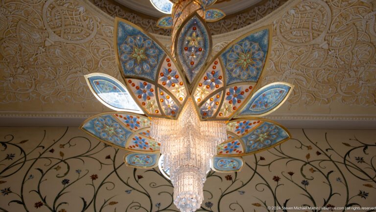 Blue-and-gold lotus-shaped crystal light beneath an intricately patterned ceiling.