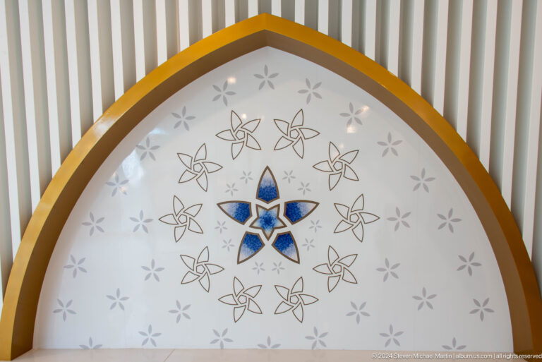 Semicircular decorative panel with a blue central star, gray motifs, and gold border.