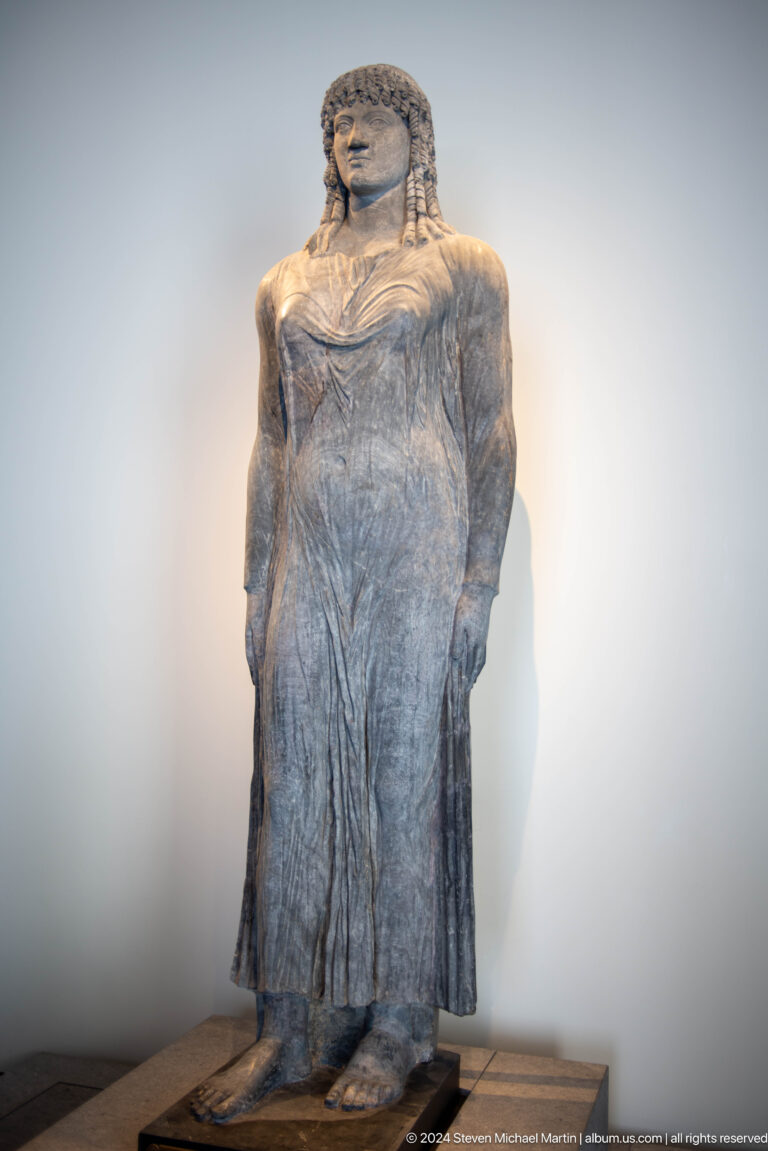 Weathered draped stone figure at Louvre Abu Dhabi.