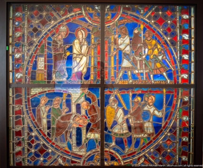 Vivid medieval stained glass with narrative scenes at Louvre Abu Dhabi.