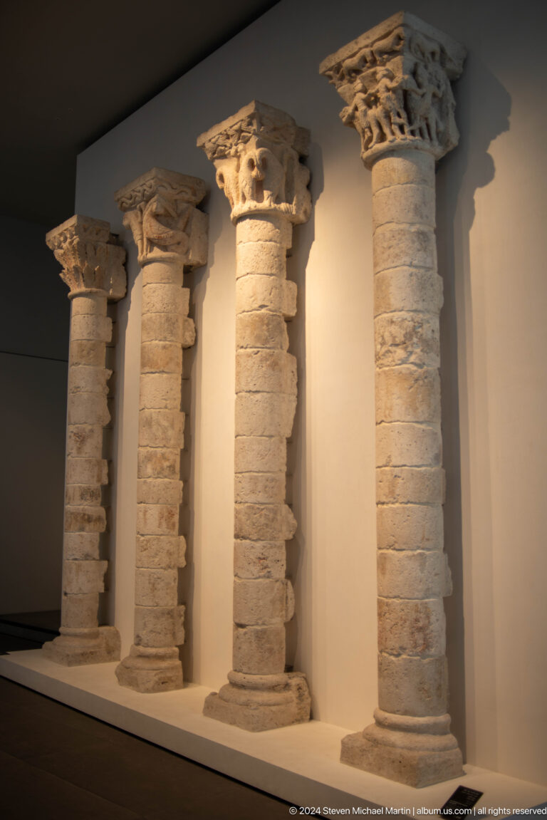 Row of carved stone columns and capitals at Louvre Abu Dhabi.