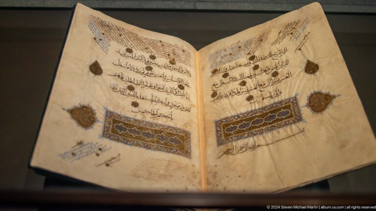 Open illuminated manuscript with musical notation at Louvre Abu Dhabi.