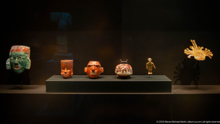 Gallery display of small vessels and sculpture at Louvre Abu Dhabi.